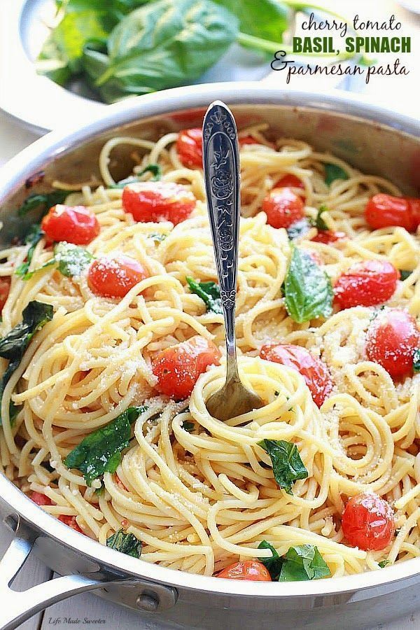 a pasta dish with tomatoes, spinach and parmesan cheese in a pan