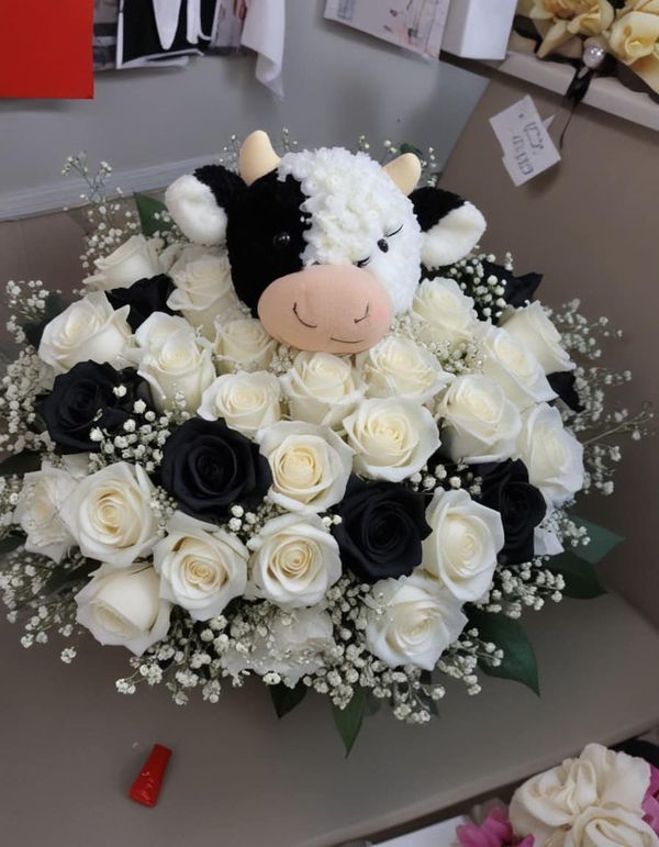 a bouquet of white and black flowers with a cow in the middle on a table