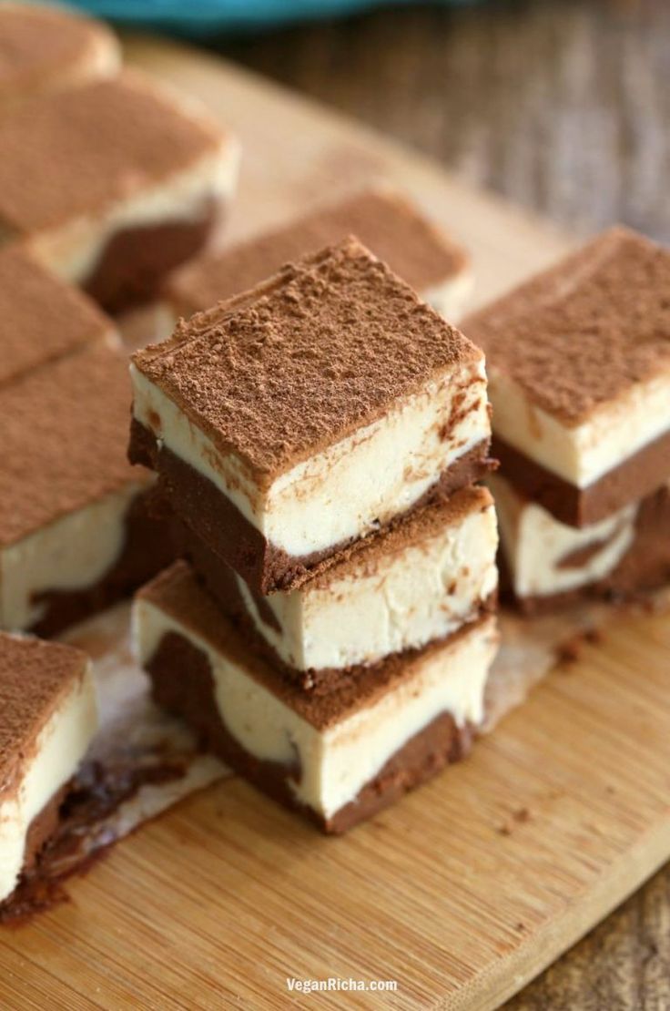 several pieces of dessert sitting on top of a wooden cutting board