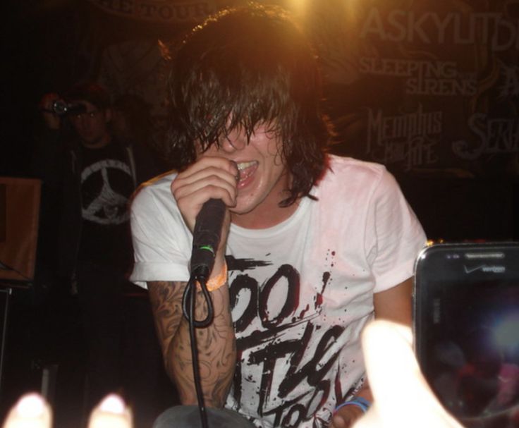 a young man holding a microphone in front of his face while sitting on a chair