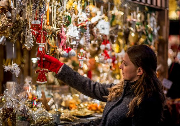 a woman looking at christmas ornaments on display in a store window with red gloves hanging from it's arms