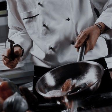 a chef is preparing food in a large pan on top of the stove with tongs