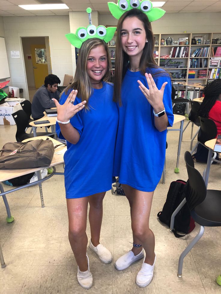 two girls in blue dresses standing next to each other and making the peace sign with their hands