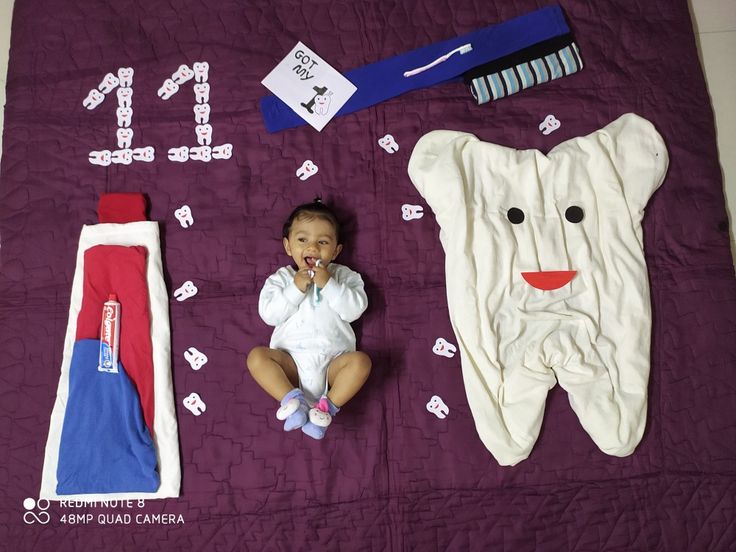 a baby is laying on a purple blanket next to toothbrushes and other items