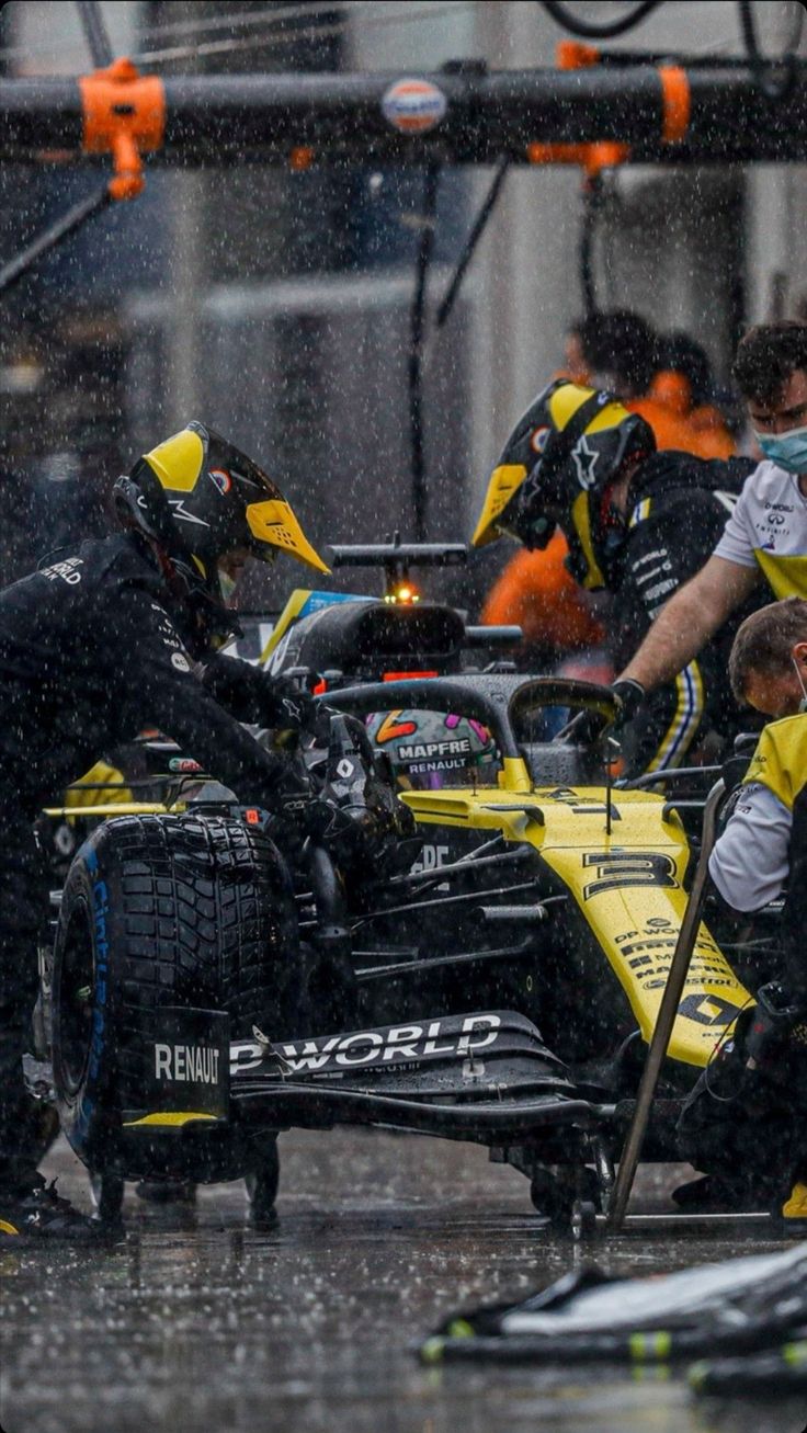 the mechanics work on a racing car in the rain