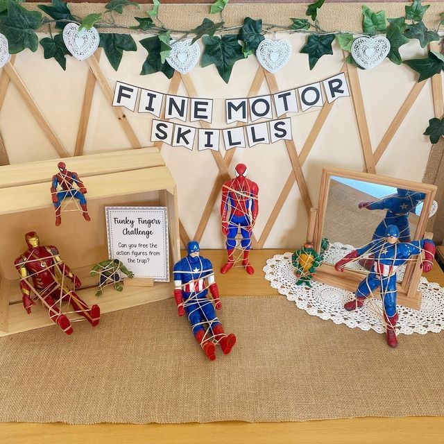 some figurines are on display in front of a wooden box with a sign that says fine motor skills