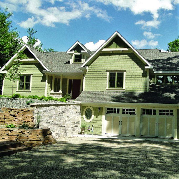 a large green house with two car garages on the front and side of it