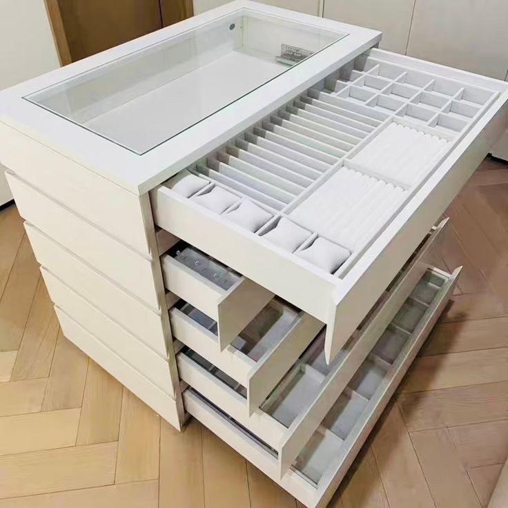 a white cabinet with drawers on top of it in the middle of a wooden floor