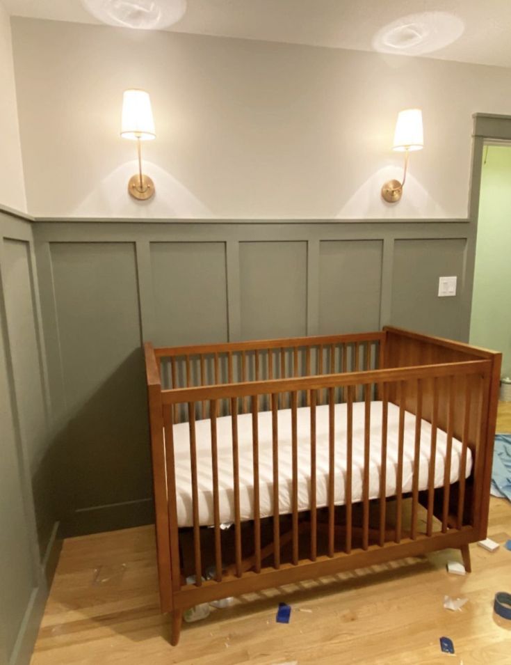 a baby crib in the corner of a room that has been painted green and white