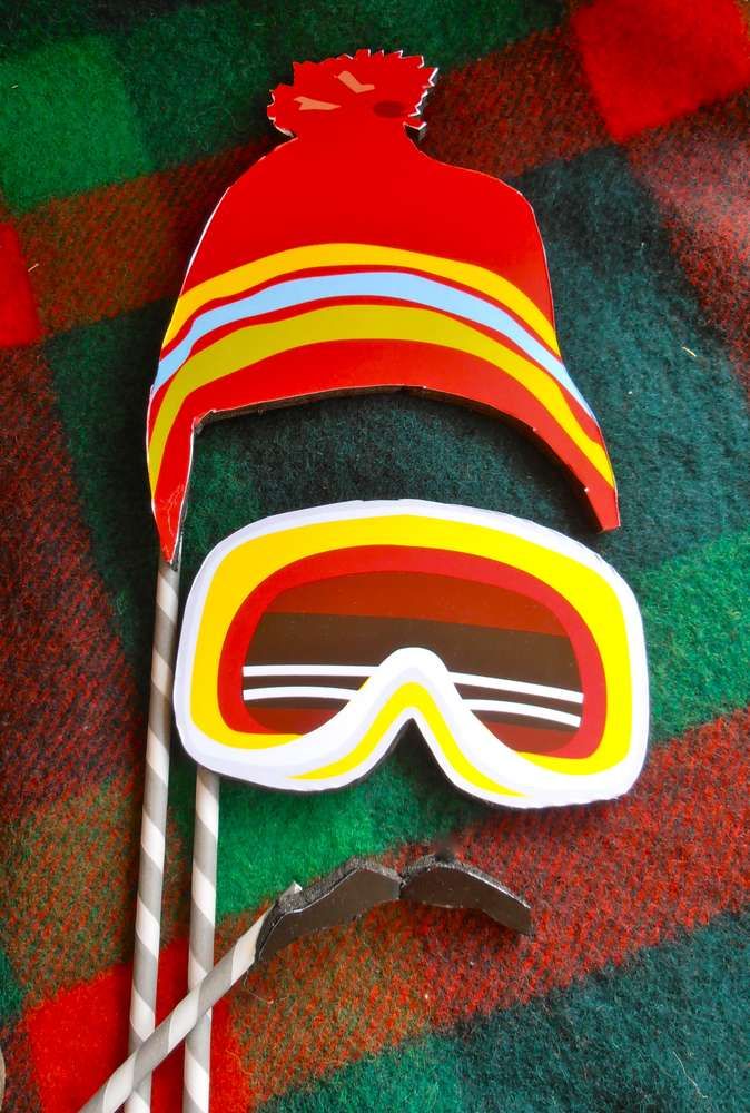 a pair of ski goggles and two pairs of tongs on a plaid tablecloth