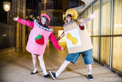 two people dressed up as food characters in front of a building at night, one holding a cardboard box and the other wearing a paper bag