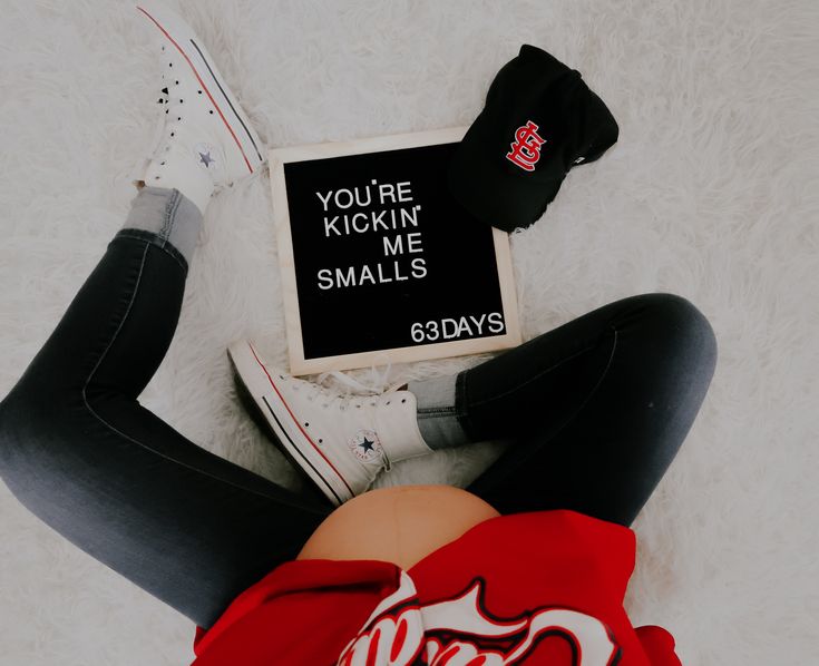 a woman laying on the floor with her legs crossed, wearing black leggings and a red shirt