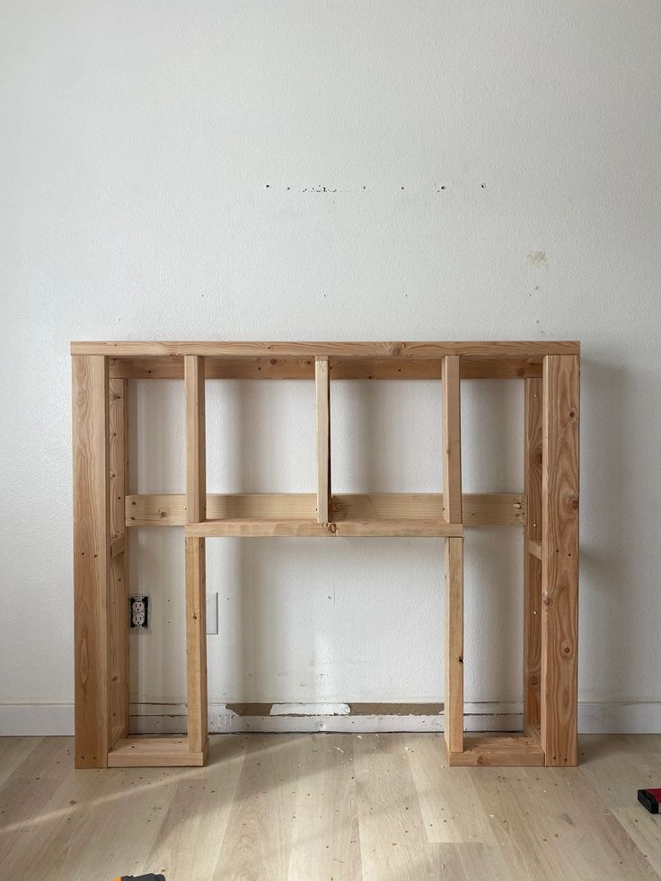 a wooden shelf sitting on top of a hard wood floor next to a white wall