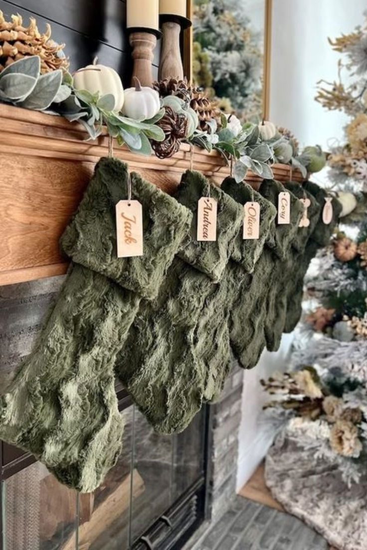 christmas stockings hanging on the mantle in front of a fireplace with pine cones and greenery