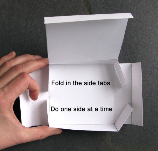 someone is holding an origami box that says fold in the side tabs do one side at a time