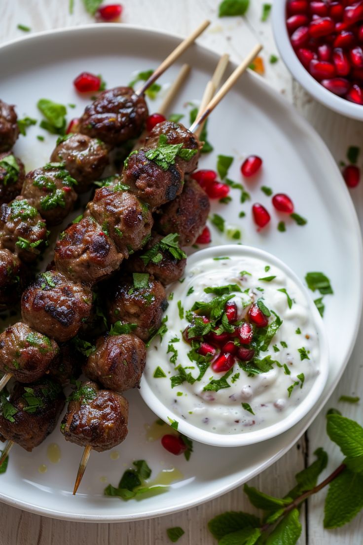 skewers of meat and vegetables on a white plate with pomegranate