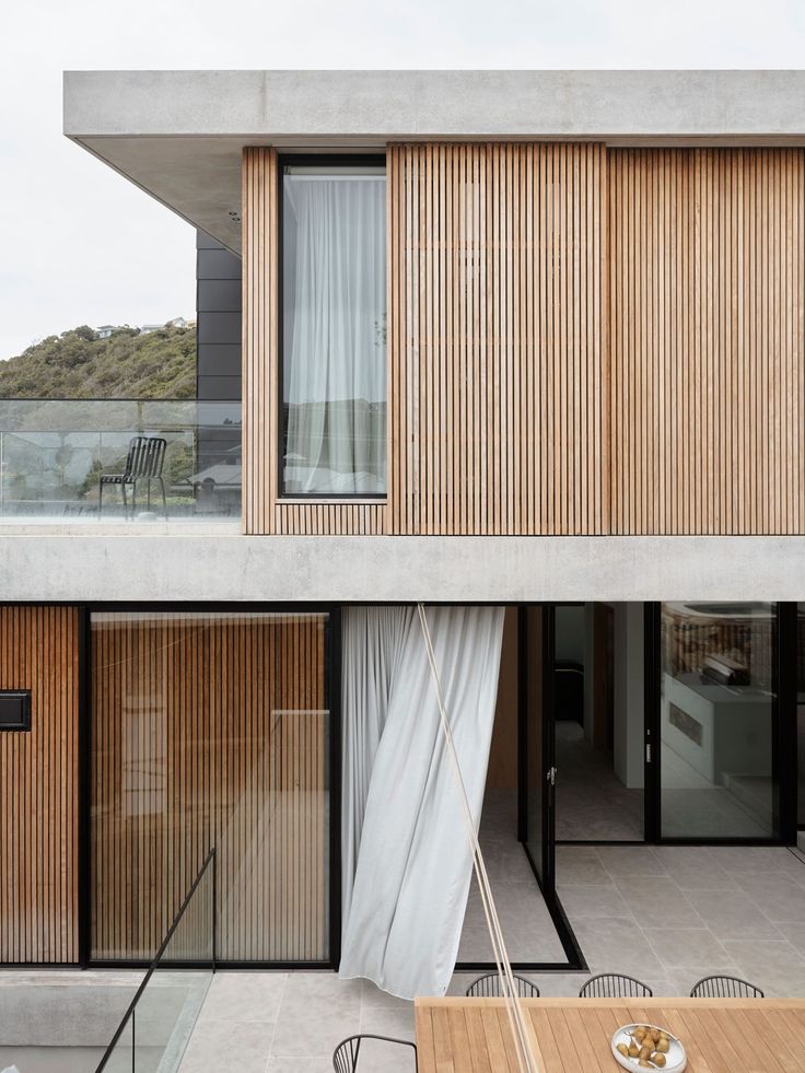 an outdoor dining area with wooden slatted walls and sliding glass doors on the side