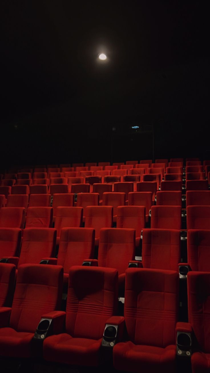 rows of red seats in an empty auditorium at night with the moon shining above them