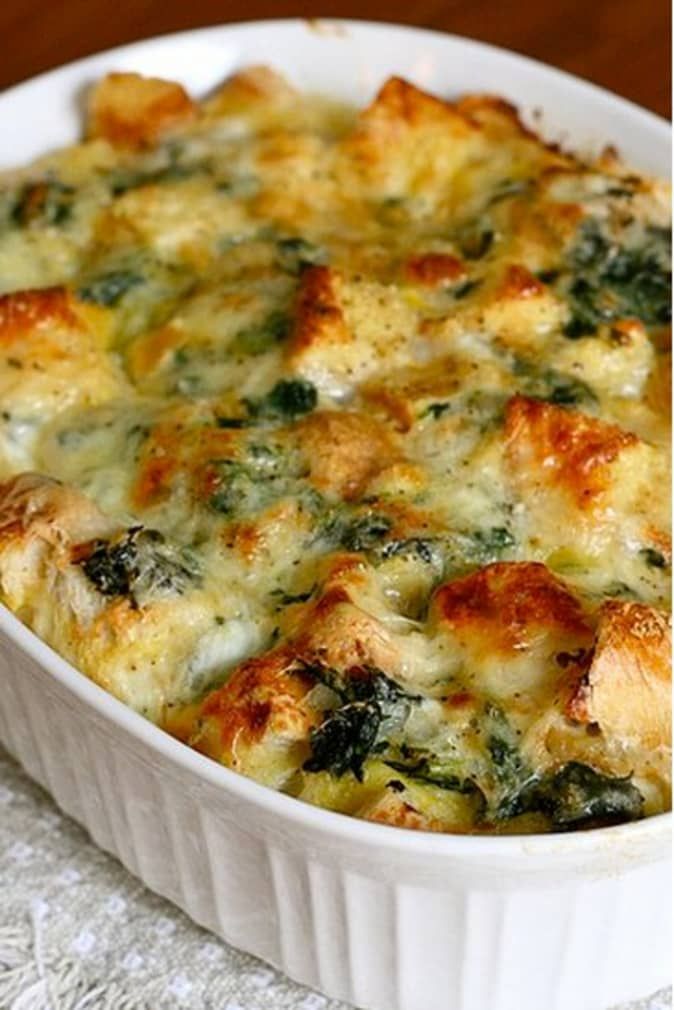 a casserole dish with cheese and spinach in it on a white cloth