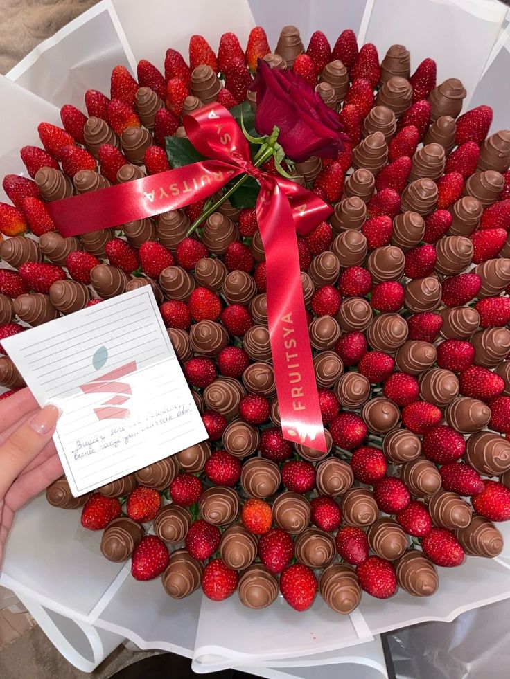 a large wreath made out of chocolate covered strawberries with a red ribbon around it