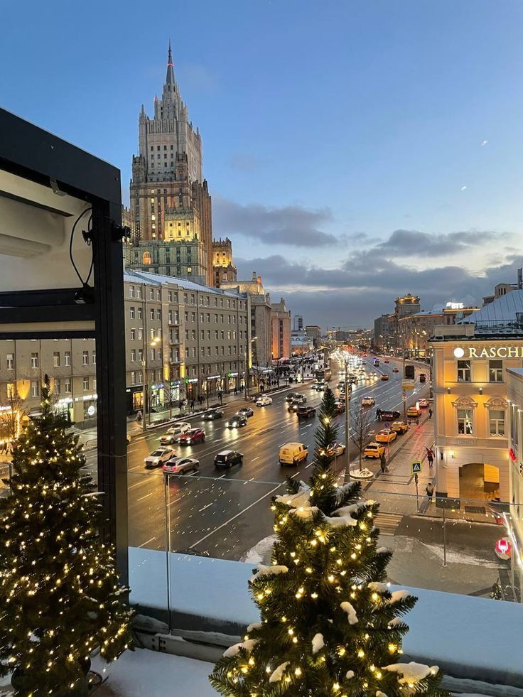 christmas trees are on the windowsill in front of a city street with traffic and tall buildings