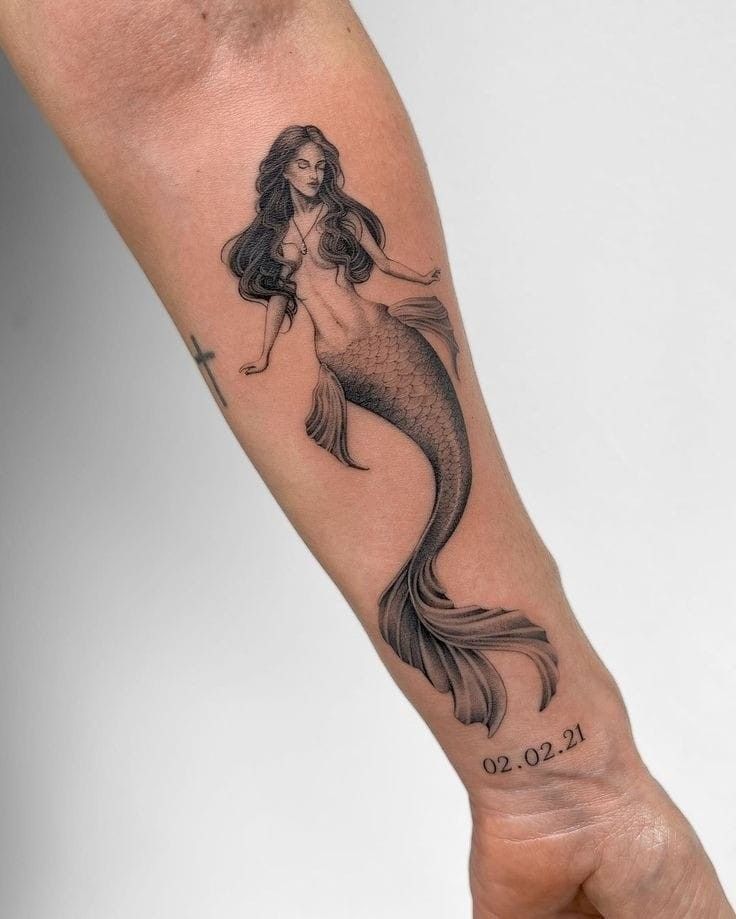 a woman's arm with a mermaid tattoo on it