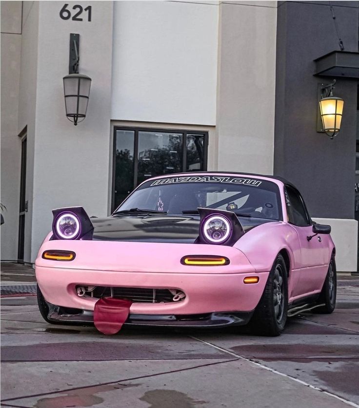 a pink sports car parked in front of a building