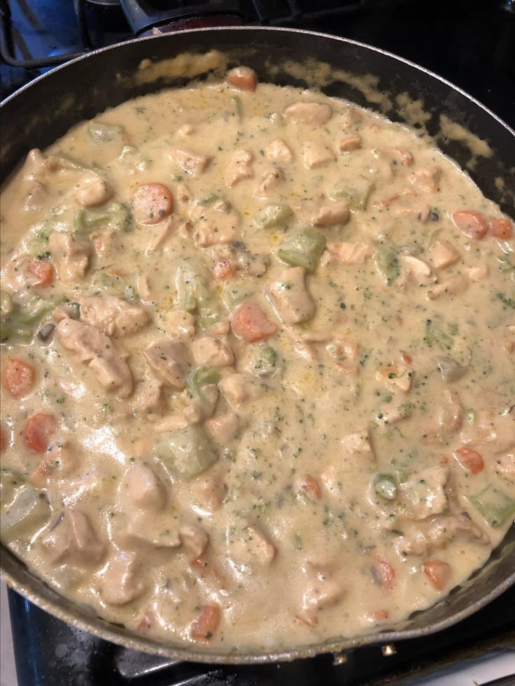 a skillet filled with chicken and veggies on top of a gas stove