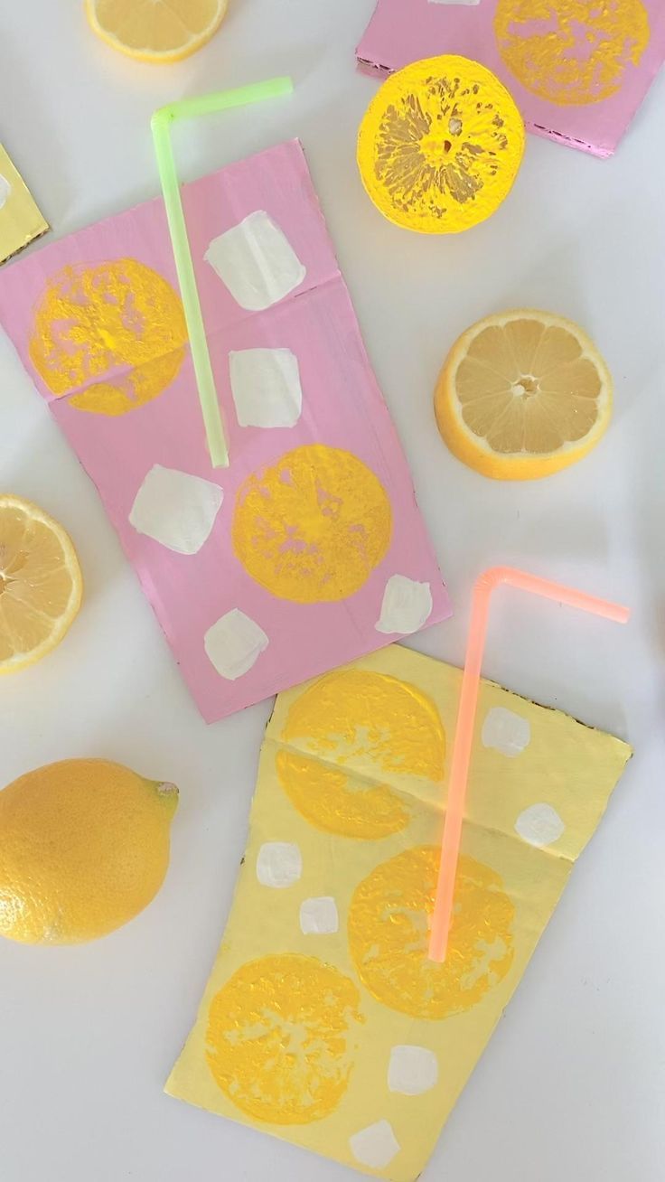 oranges and lemon slices cut out on paper with drinking straws in them, sitting next to each other