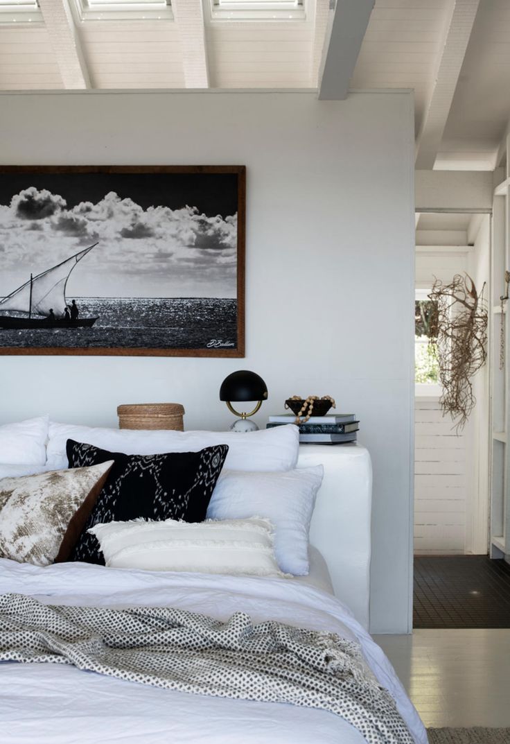 a white bed sitting under a painting on the wall