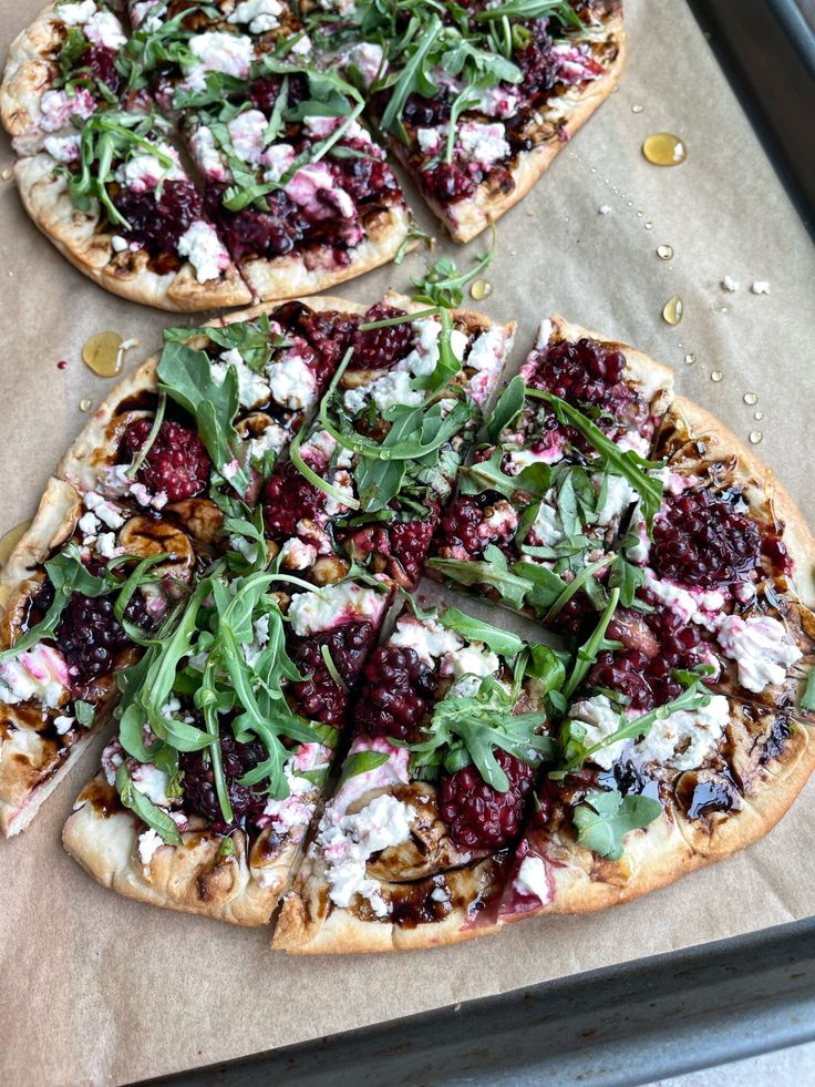 two pizzas sitting on top of a pan covered in toppings