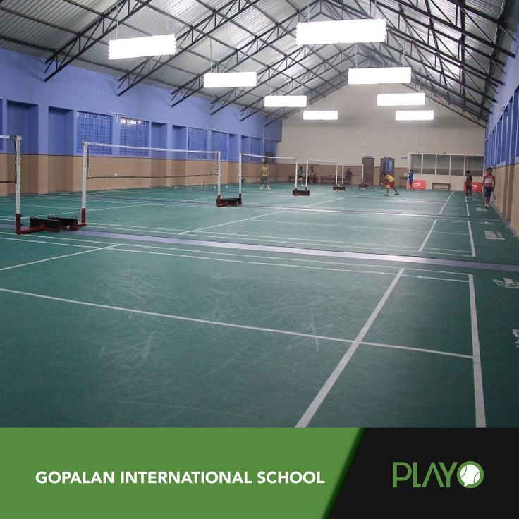 an indoor tennis court with blue walls and green flooring is shown in this image