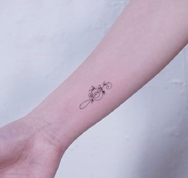 a small flower tattoo on the left inner arm and wrist, is shown in black ink