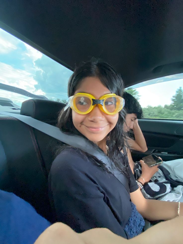 a woman wearing yellow goggles in the back seat of a car