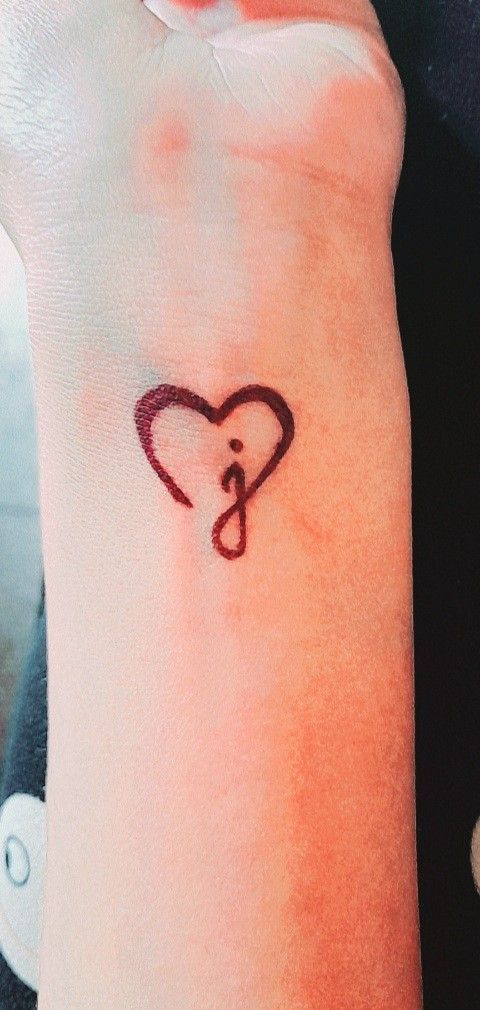 a person with a heart tattoo on their left arm and the letter c in the middle