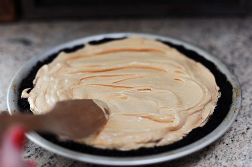 a person is spreading frosting on top of a cake in a pie pan with a spatula