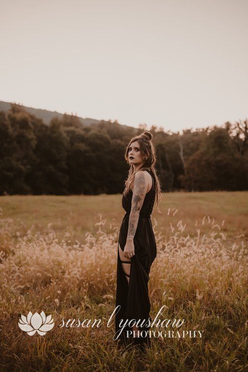 a woman in a black dress standing in a field