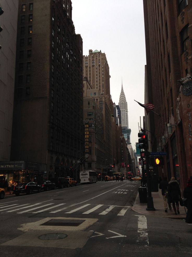 an empty city street with tall buildings and traffic lights on both sides in the distance