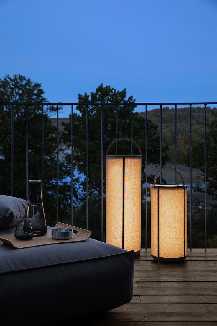 two lamps sitting on top of a wooden floor next to a bed in front of a balcony