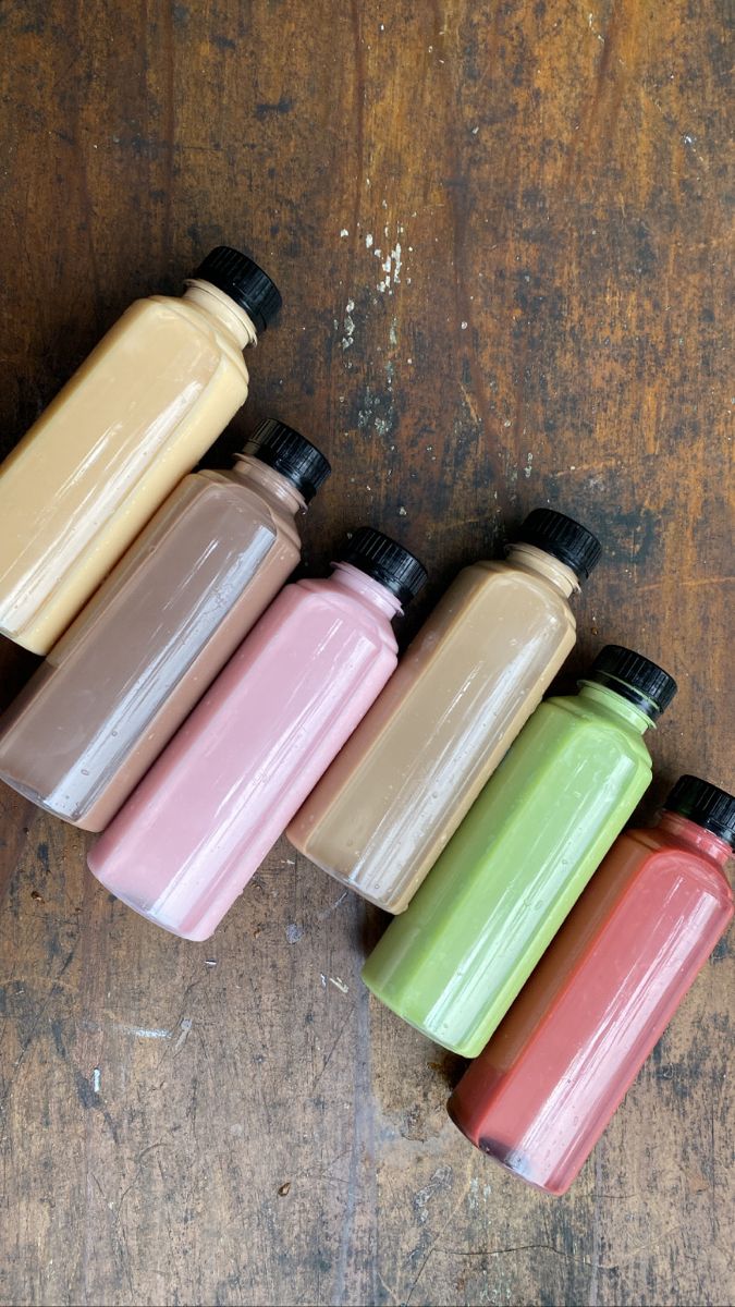 five different colored bottles sitting on top of a wooden table