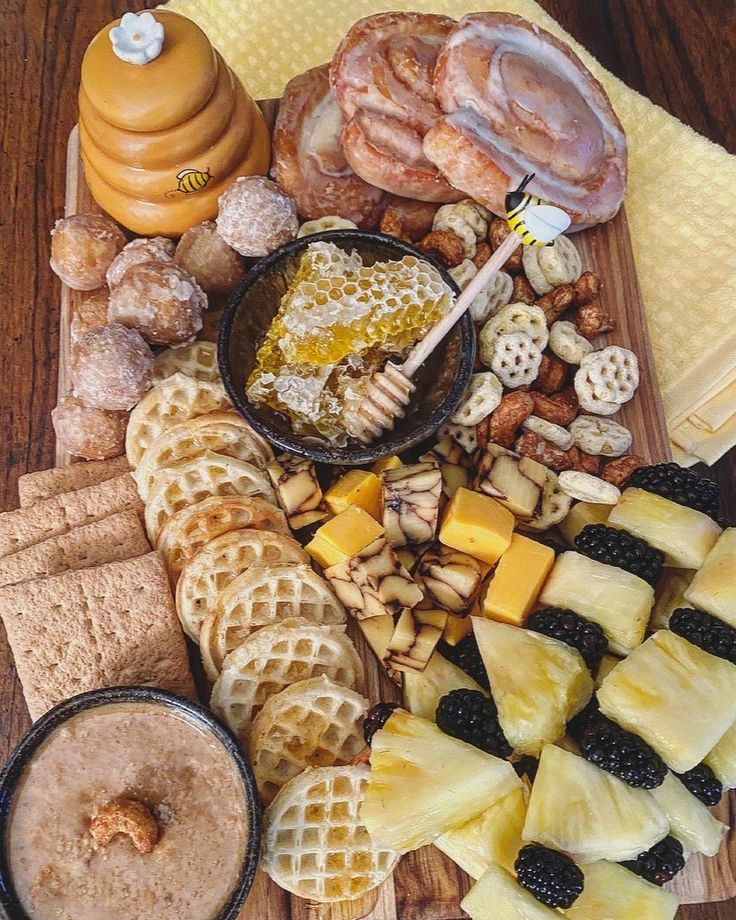 a wooden table topped with lots of different types of cheeses and crackers on top of each other