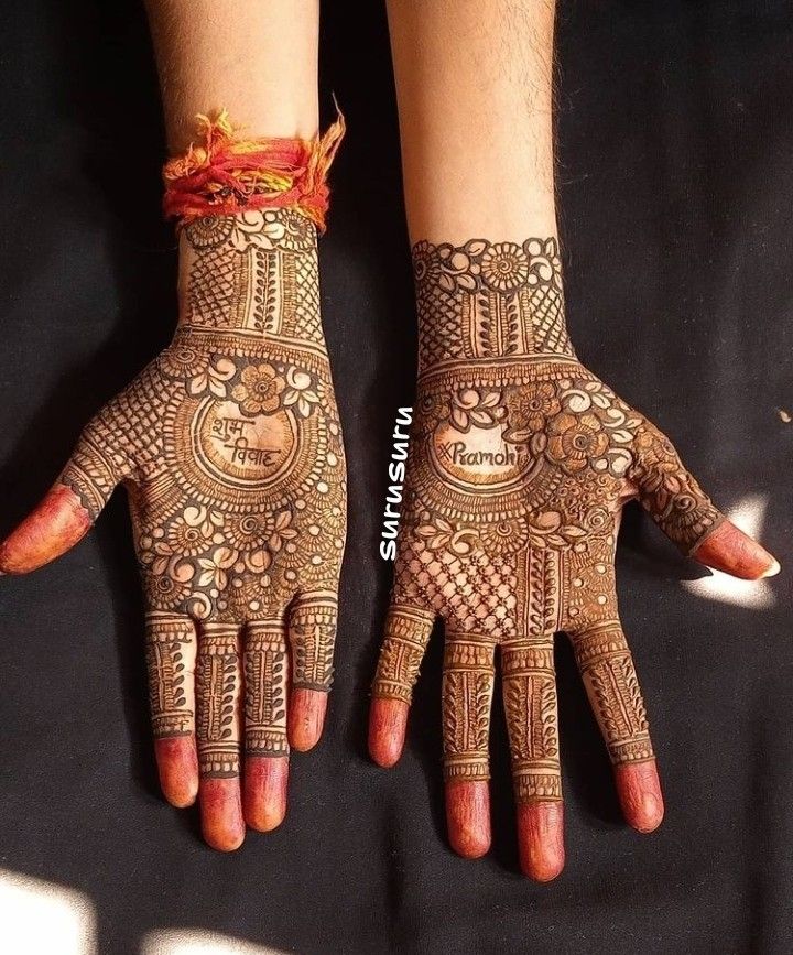 two hands with henna designs on them and one hand is decorated with an orange ribbon