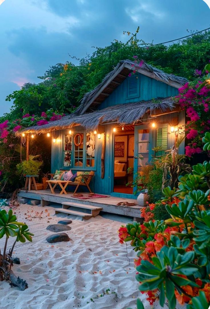 a small blue house with lights on the porch