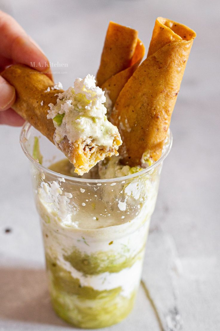 a person is dipping some food into a small cup with ice cream and other toppings