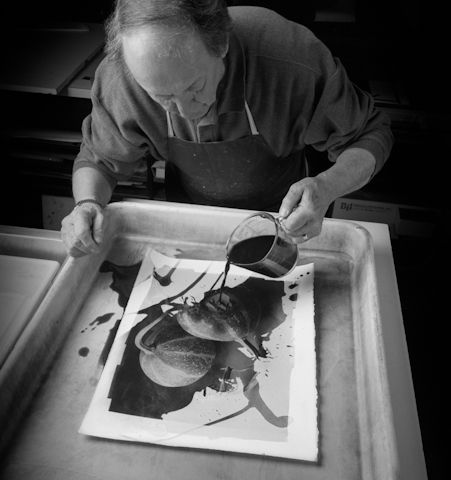 a man in an apron is painting on a piece of paper with black and white ink