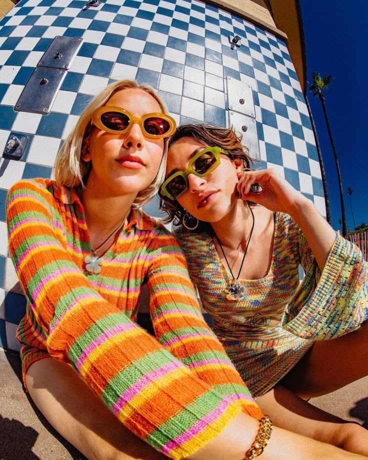 two women sitting on the ground wearing sunglasses