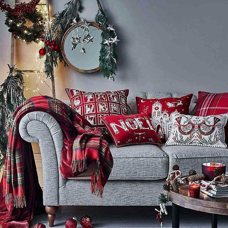 a living room decorated for christmas with red and white decorations on the walls, plaid throw blankets, poinsettis and wreaths