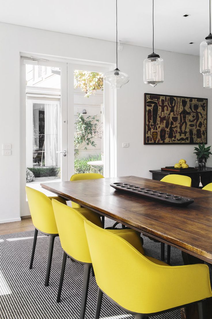 a dining room with yellow chairs and a wooden table