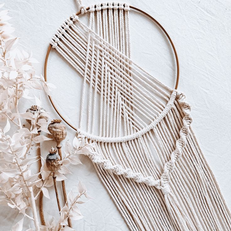 a close up of a macrame and flowers on a white surface with an object in the background