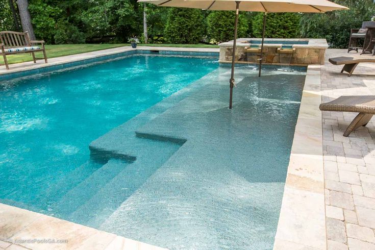 an empty swimming pool surrounded by chairs and umbrellas